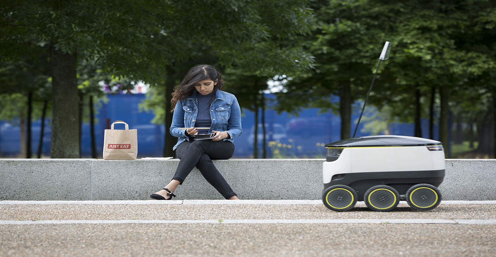 Woman with robot on sidewalk in city