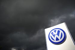 Volkswagen logo on sign under dark clouds Volkswagen logo on sign under dark clouds