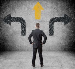 Man in suit standing in front of arrows pointing multiple directions Man in suit standing in front of arrows pointing multiple directions