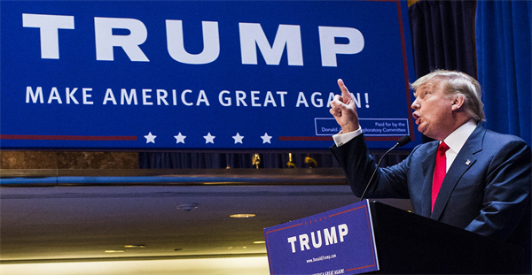 Donald Trump pointing up in front of campaign sign