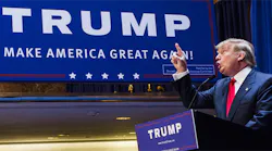 Donald Trump pointing up in front of campaign sign