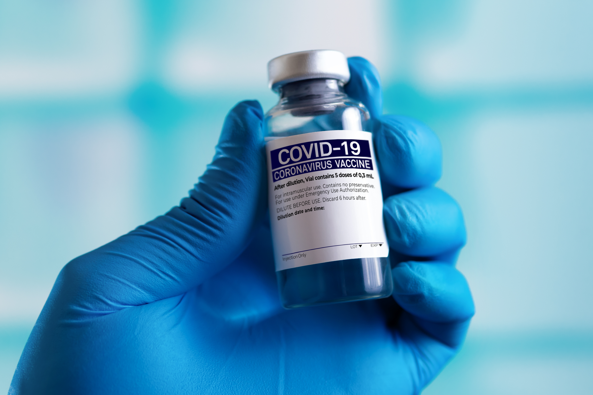 Hand holding COVID vaccine vial