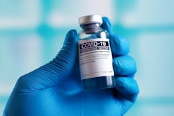 Hand holding COVID vaccine vial Hand holding COVID vaccine vial