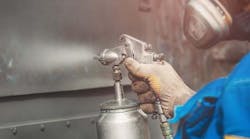 Worker spraying anti-corrosion coating on metal. Worker spraying anti-corrosion coating on metal.