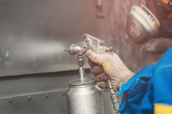 Worker spraying anti-corrosion coating on metal. Worker spraying anti-corrosion coating on metal.