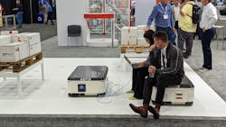 Employees use an ABB autonomous mobile robot (AMR) as a seat at the company's Automate booth. Employees use an ABB autonomous mobile robot (AMR) as a seat at the company's Automate booth.