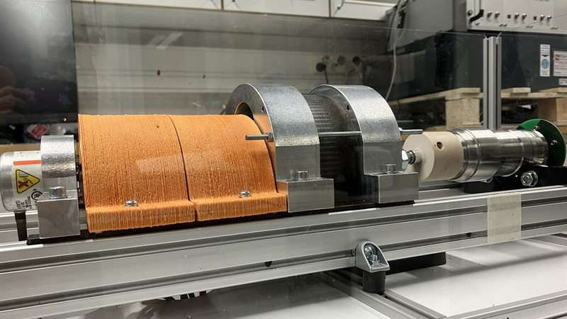 Electric machine with 3D printed parts in the middle, orange 3D printed cable cover on the left, and smart shaft as a load on the right.