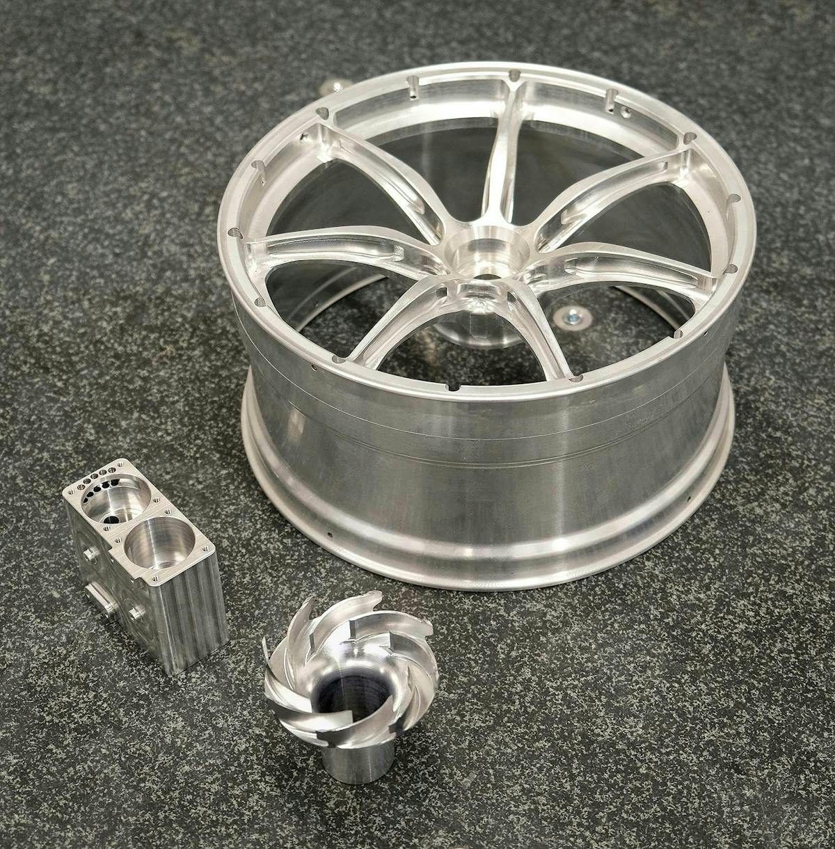 Typical components, all machined from solid aluminum, inspected by Driven Engineering on the LK CMM. Clockwise from the back: the scaled-down race car wheel, an impeller, and an aircraft fuel pump component.
