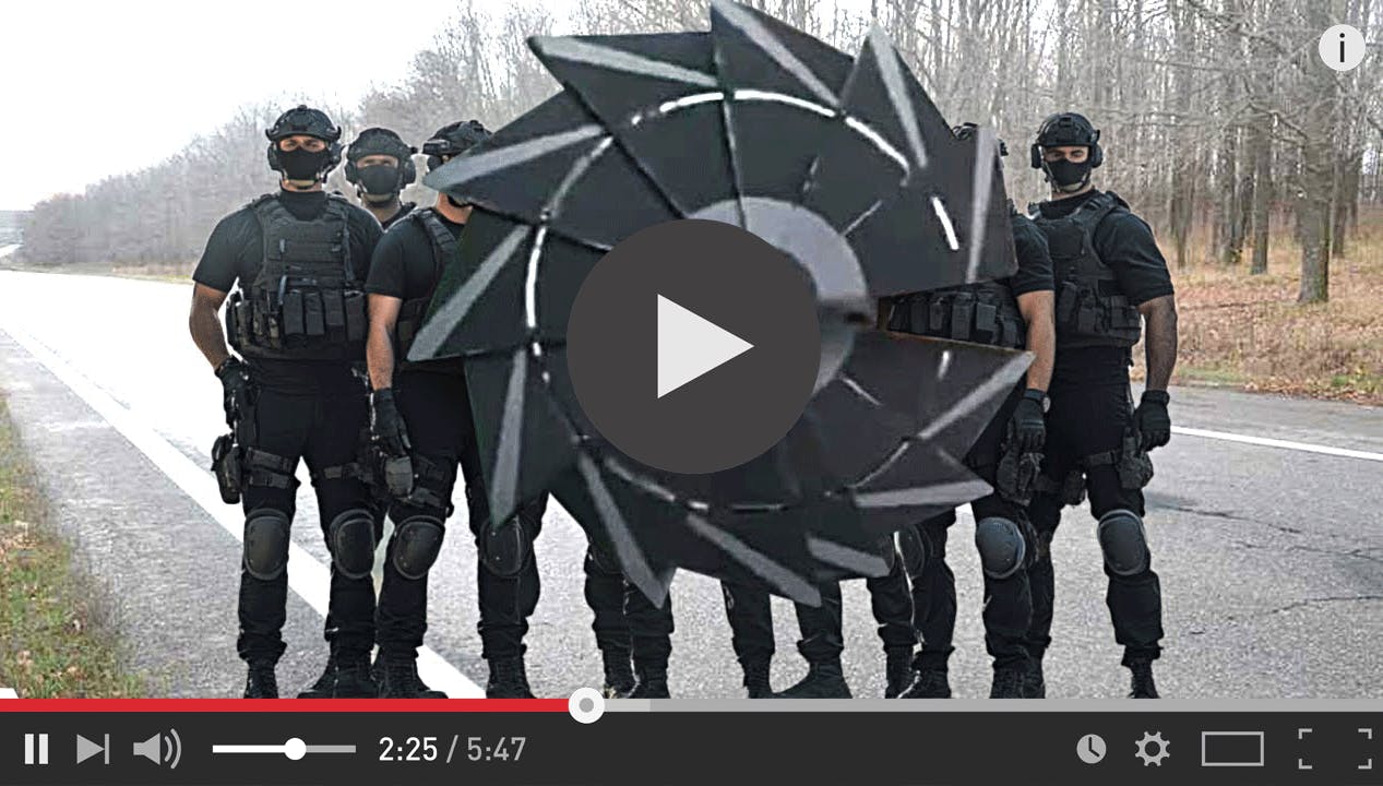 A screengrab from a YouTube video of a group of army men with a large circular blade invention in front of them