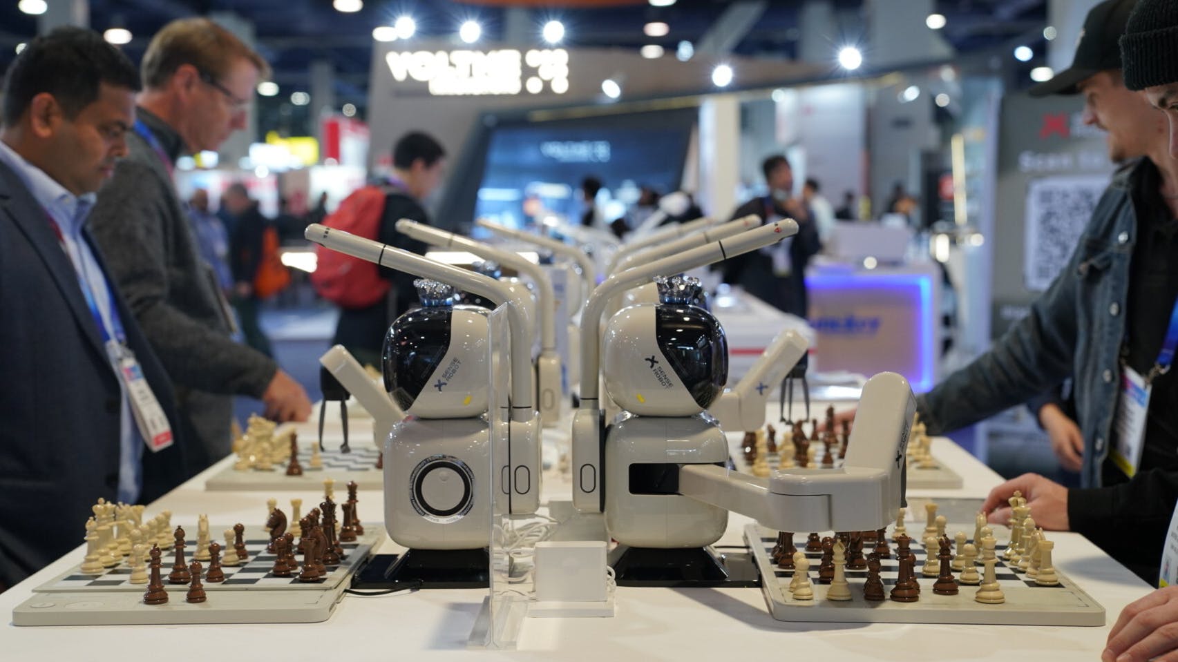 SenseRobot's Chess robot on display with CES attendess interacting and playing chess with them at a table.