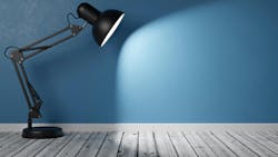 Powered On Black Desk Lamp on Wooden Floor in the Room with blue wall Powered On Black Desk Lamp on Wooden Floor in the Room with blue wall