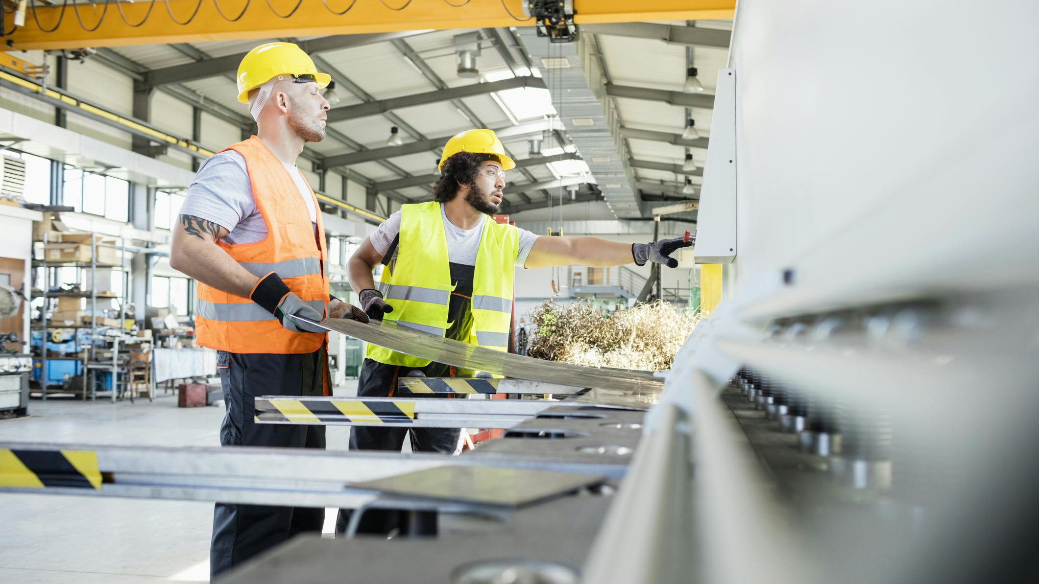 Male manual workers manufacturing sheet metal at industry.