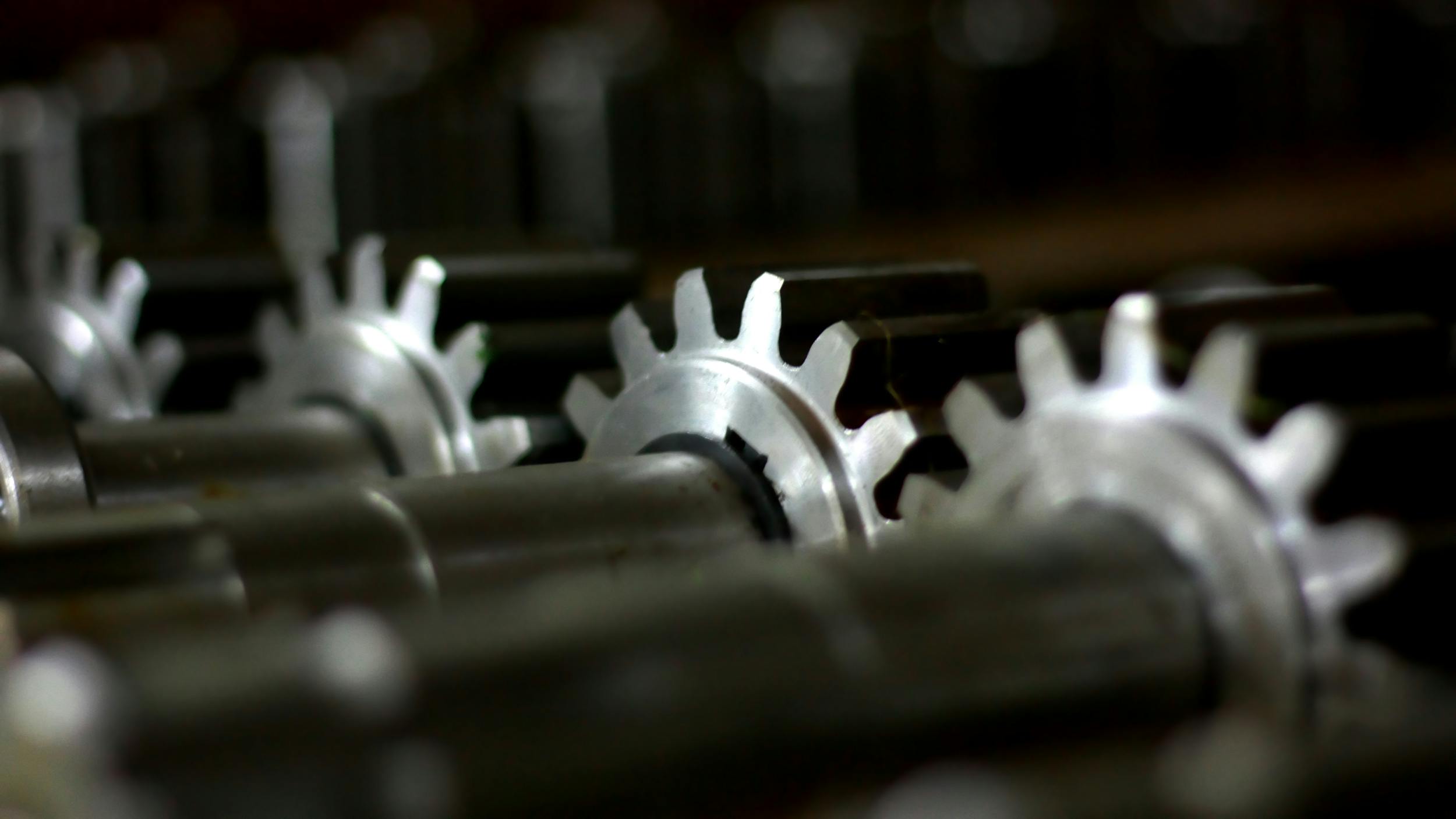 Close-up of gears on shafts, dimly lit