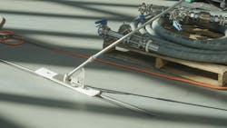 Slot dog drain cleaning tool in use on grey floor Slot dog drain cleaning tool in use on grey floor