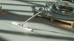 Slot dog drain cleaning tool in use on grey floor