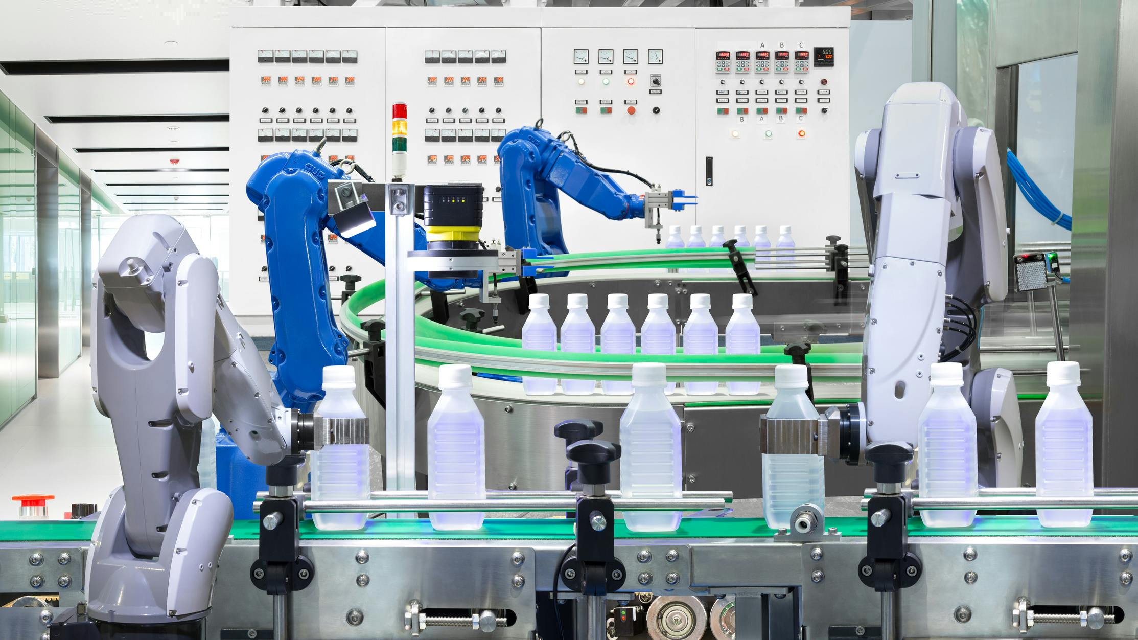 Robotic arm holding water bottles on production line in factory, Industry 4. 0 concept