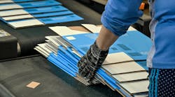 Worker gathering printed, flat carboard boxes ready for assembly off the line. Worker gathering printed, flat carboard boxes ready for assembly off the line.