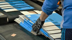 Worker gathering printed, flat carboard boxes ready for assembly off the line. Worker gathering printed, flat carboard boxes ready for assembly off the line.